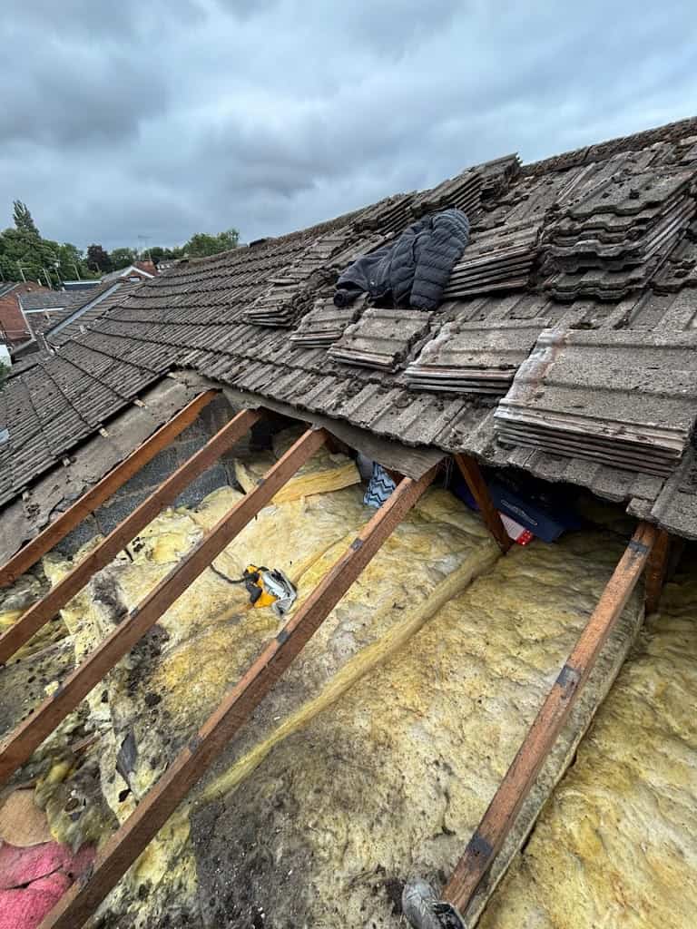 Old damaged roof tiles, battons, and insulation being removed on home