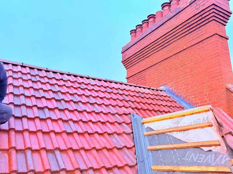 Clay tile pitched roof with red brick chimney stack repair