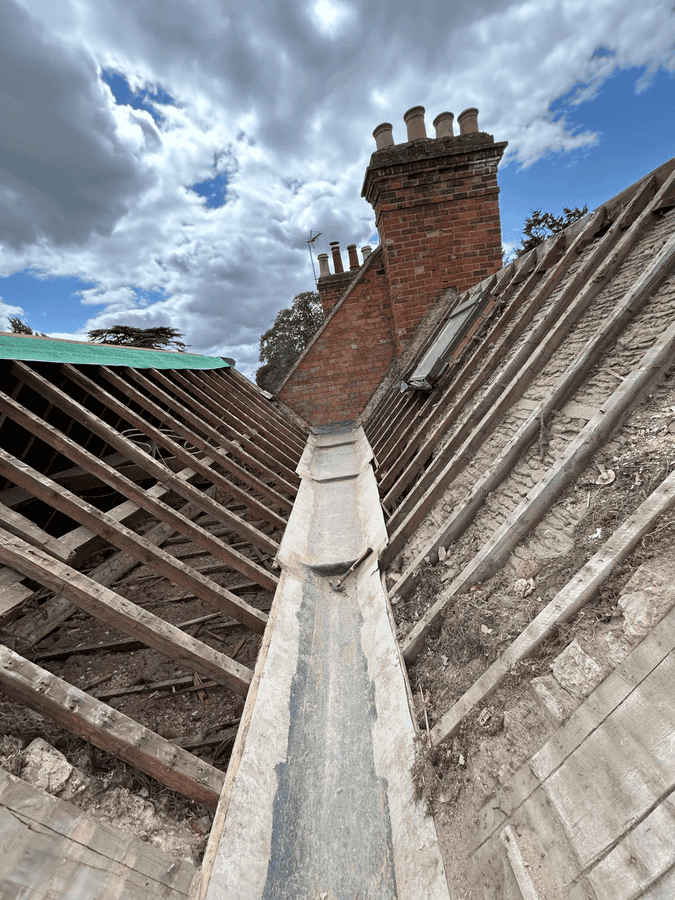 Old wooden beams exposed during roof and valley repair